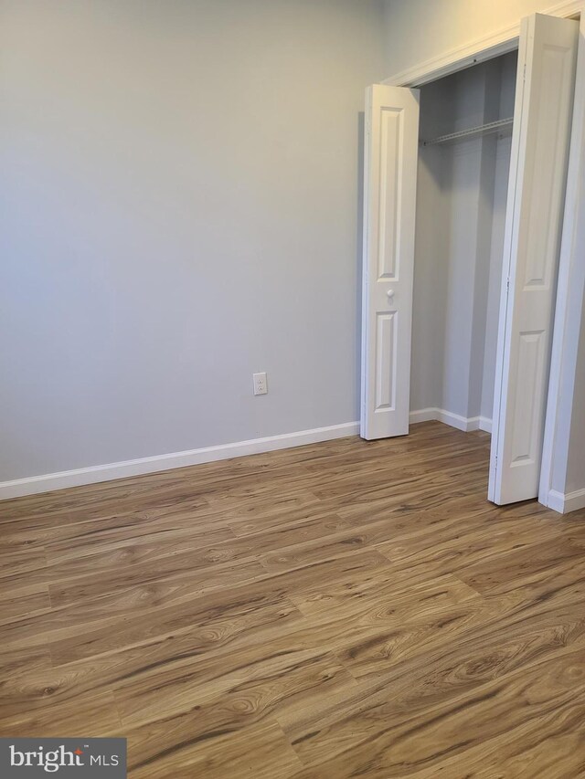 unfurnished bedroom with a closet, baseboards, and wood finished floors