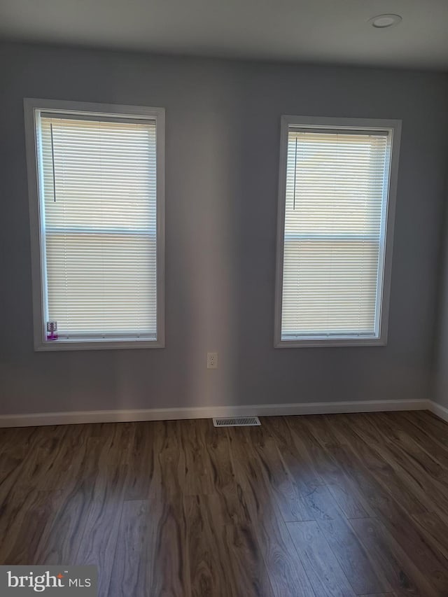 empty room with baseboards, visible vents, and wood finished floors