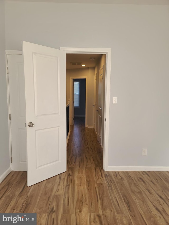 hallway with visible vents, baseboards, and wood finished floors