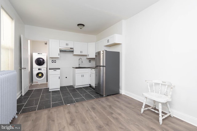 kitchen with stainless steel fridge, white cabinets, dark hardwood / wood-style flooring, sink, and stacked washer and clothes dryer