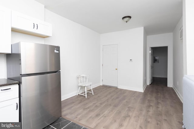 kitchen with white cabinets, stainless steel fridge, and hardwood / wood-style flooring