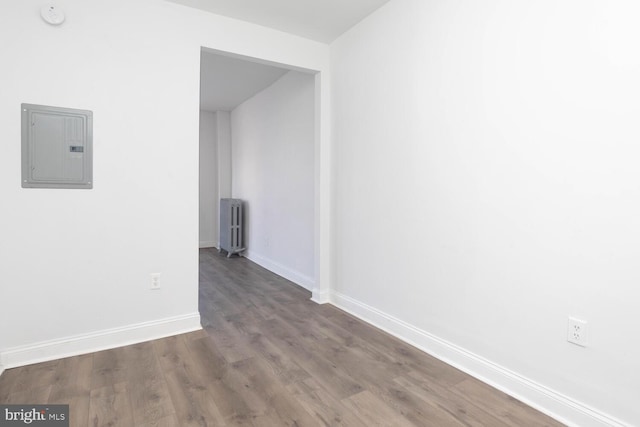 hallway featuring electric panel, wood-type flooring, and radiator