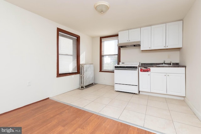 kitchen featuring sink, radiator heating unit, white cabinetry, white stove, and light hardwood / wood-style flooring