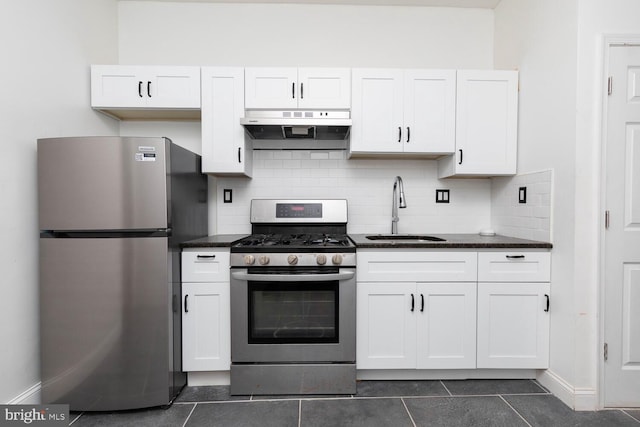 kitchen with appliances with stainless steel finishes, sink, dark tile patterned floors, and white cabinets