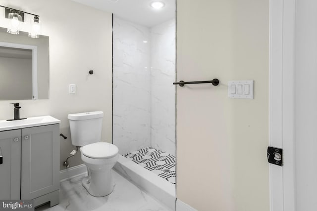 bathroom with vanity, a tile shower, and toilet