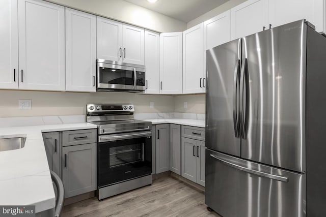 kitchen with light hardwood / wood-style flooring, gray cabinetry, stainless steel appliances, and white cabinets