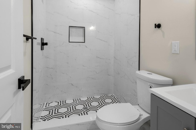 bathroom with toilet, vanity, and a tile shower