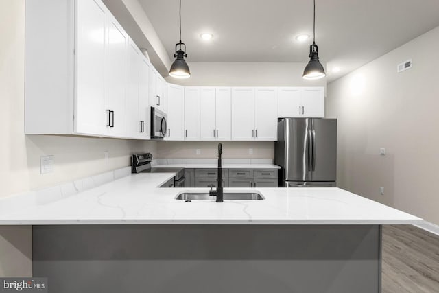 kitchen with appliances with stainless steel finishes, sink, decorative light fixtures, white cabinets, and light stone counters