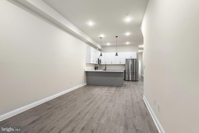 kitchen with light hardwood / wood-style flooring, hanging light fixtures, stainless steel appliances, kitchen peninsula, and white cabinets