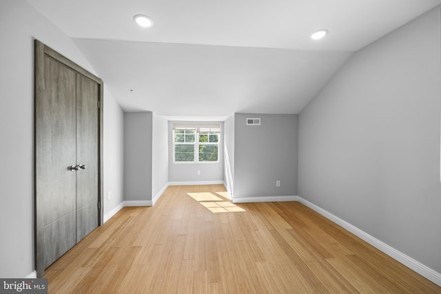 unfurnished bedroom with a closet, lofted ceiling, and light wood-type flooring