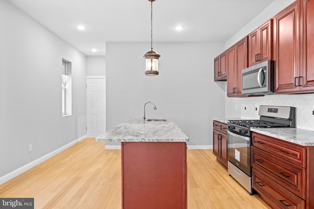 kitchen featuring light stone counters, light hardwood / wood-style flooring, stainless steel appliances, sink, and decorative light fixtures