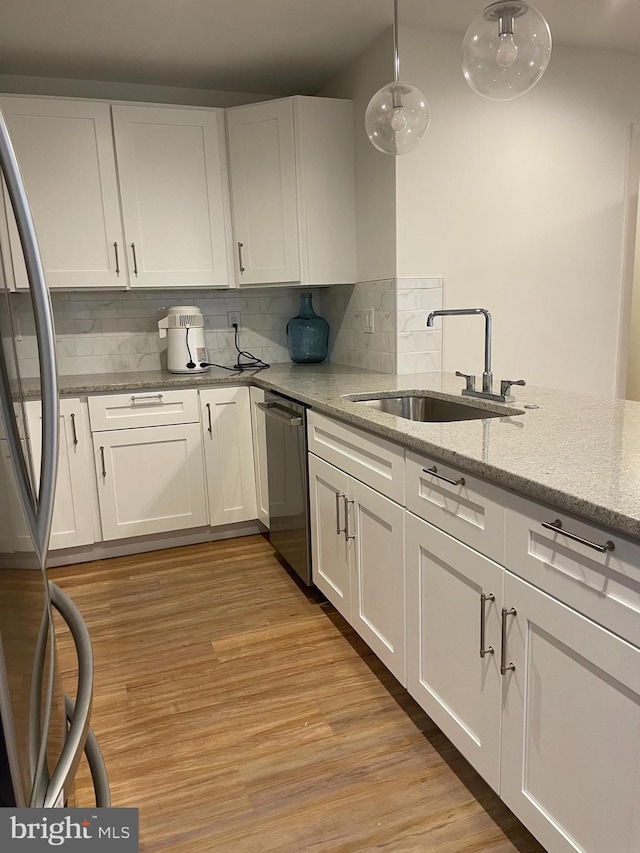 kitchen featuring light stone countertops, light wood-type flooring, hanging light fixtures, white cabinetry, and stainless steel appliances