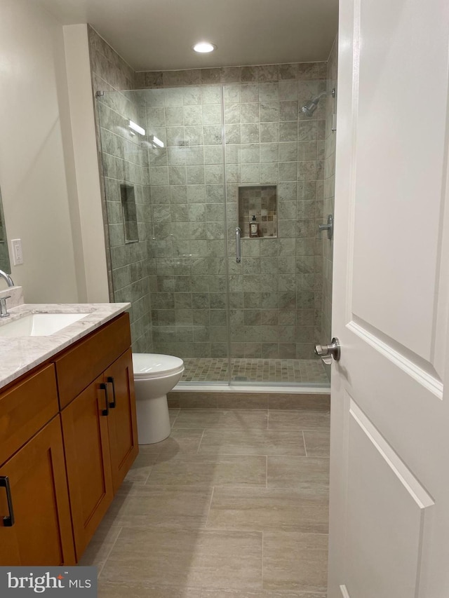 bathroom featuring vanity, toilet, a shower with shower door, and tile patterned flooring