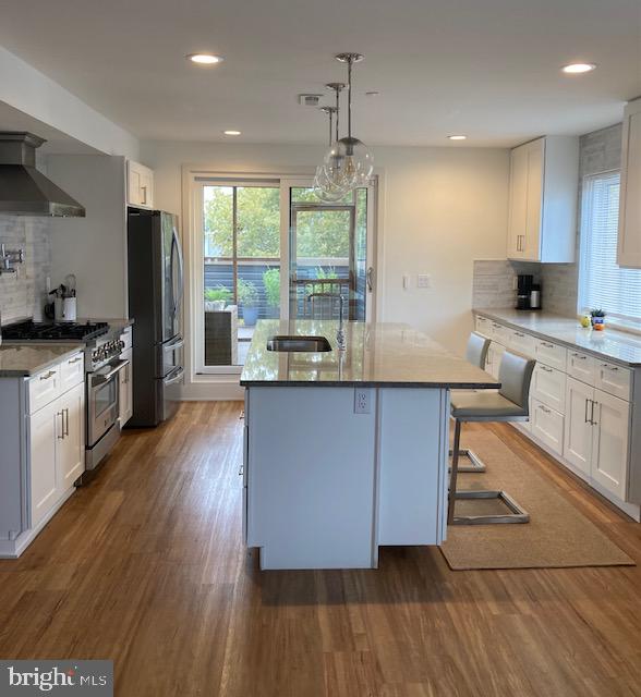 kitchen featuring hanging light fixtures, appliances with stainless steel finishes, dark hardwood / wood-style flooring, and white cabinets