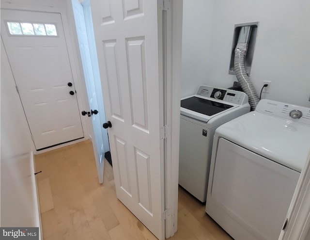 clothes washing area featuring light hardwood / wood-style flooring and washer and clothes dryer