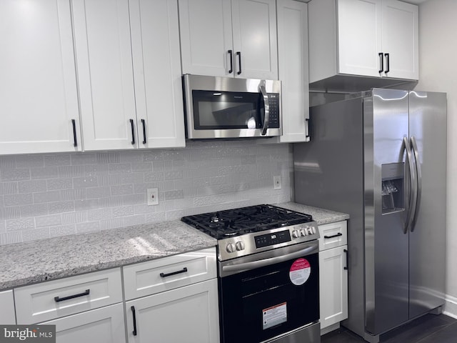 kitchen with light stone countertops, stainless steel appliances, white cabinetry, and tasteful backsplash