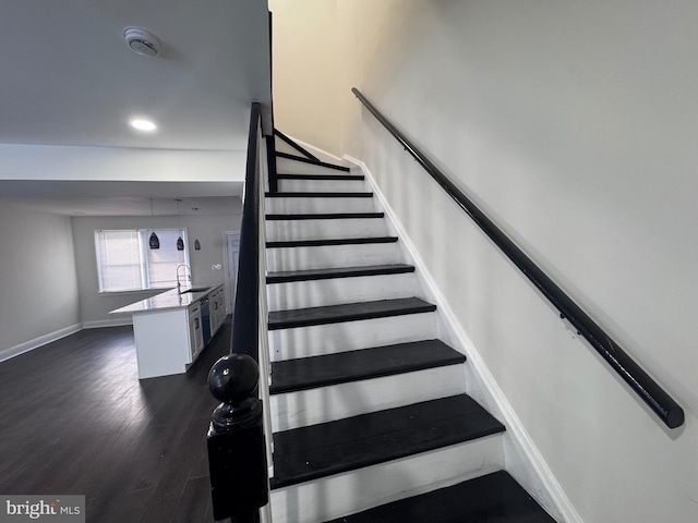 stairs featuring wood-type flooring and sink