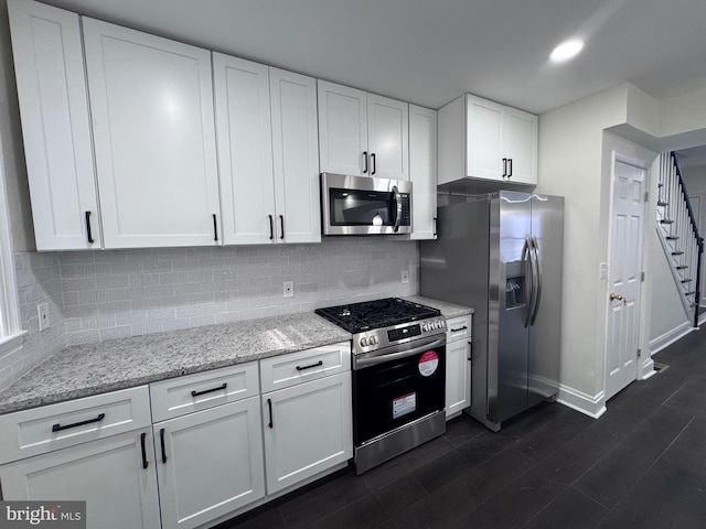 kitchen featuring white cabinets, light stone counters, stainless steel appliances, and tasteful backsplash