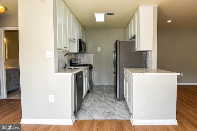 kitchen featuring sink, white cabinets, stainless steel appliances, and light wood-type flooring