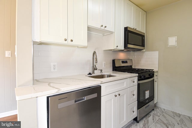 kitchen with white cabinetry, backsplash, appliances with stainless steel finishes, and light stone counters