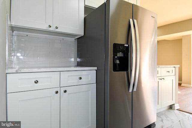 kitchen featuring white cabinetry, light stone countertops, tasteful backsplash, and stainless steel fridge with ice dispenser