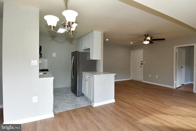 kitchen with light hardwood / wood-style floors, white cabinets, ceiling fan with notable chandelier, and backsplash