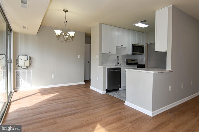 kitchen featuring an inviting chandelier, white cabinetry, sink, light hardwood / wood-style floors, and stainless steel appliances