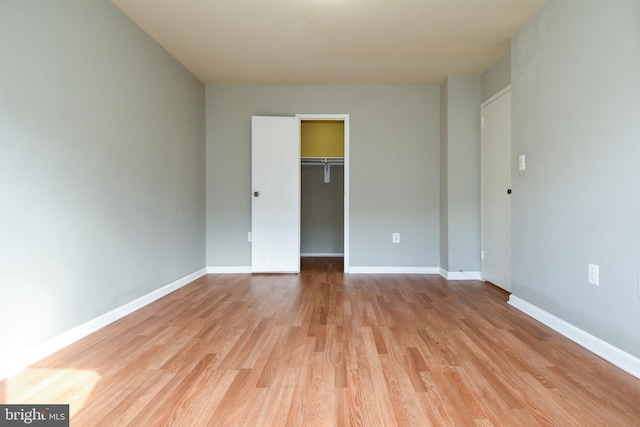 unfurnished bedroom featuring light hardwood / wood-style flooring, a closet, and a walk in closet