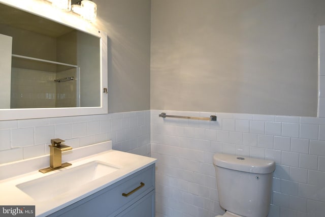 bathroom featuring toilet, walk in shower, vanity, and tile walls