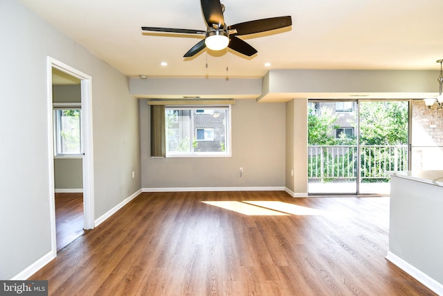 unfurnished room with ceiling fan, a healthy amount of sunlight, and dark hardwood / wood-style flooring