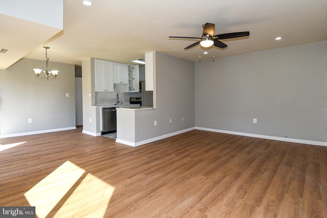 unfurnished living room featuring sink, hardwood / wood-style floors, and ceiling fan with notable chandelier