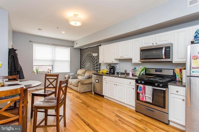 kitchen featuring white cabinetry, sink, light hardwood / wood-style floors, and appliances with stainless steel finishes