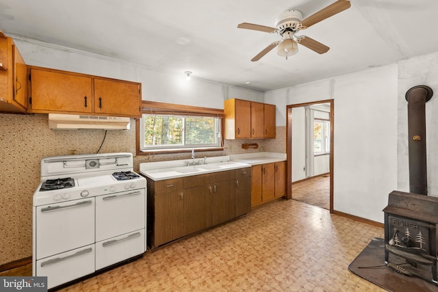 kitchen featuring sink, white stove, a wood stove, and ceiling fan