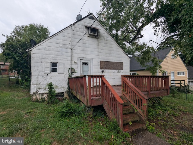 rear view of house featuring a wooden deck and a lawn