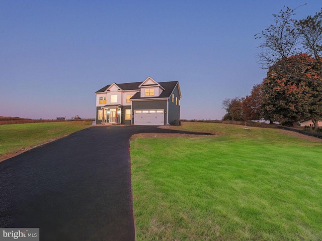 view of front of home featuring a lawn, a rural view, and a garage