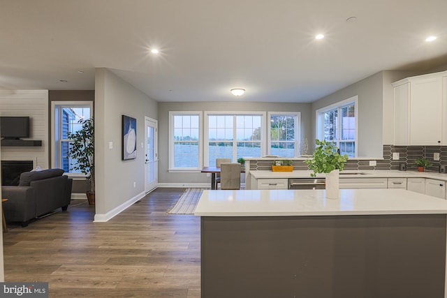 kitchen featuring a healthy amount of sunlight, white cabinets, hardwood / wood-style flooring, and a water view