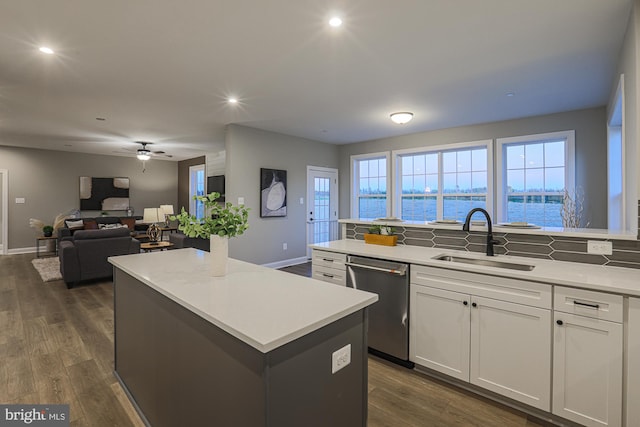 kitchen with dark hardwood / wood-style floors, sink, a center island, stainless steel dishwasher, and white cabinets