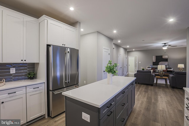 kitchen featuring backsplash, stainless steel fridge, a center island, white cabinets, and dark hardwood / wood-style flooring