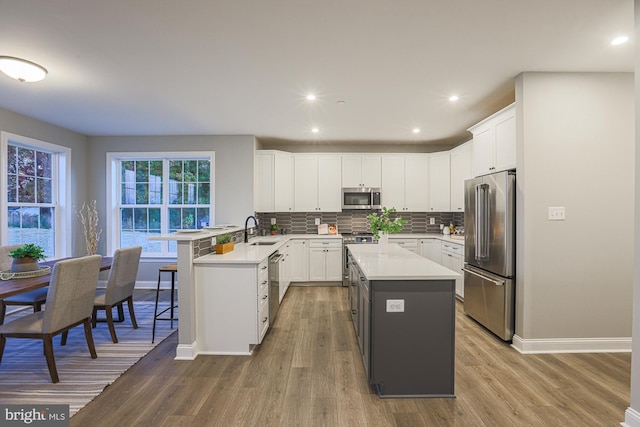 kitchen with hardwood / wood-style floors, sink, a kitchen island, and stainless steel appliances