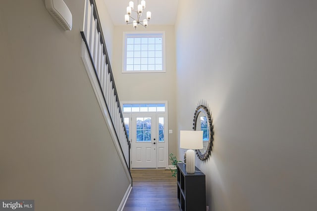 foyer featuring dark wood-type flooring, high vaulted ceiling, an AC wall unit, and a chandelier