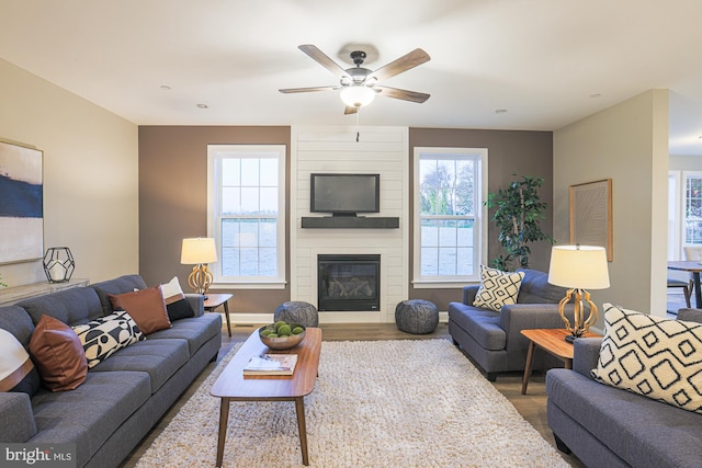 living room featuring ceiling fan, wood-type flooring, and a fireplace