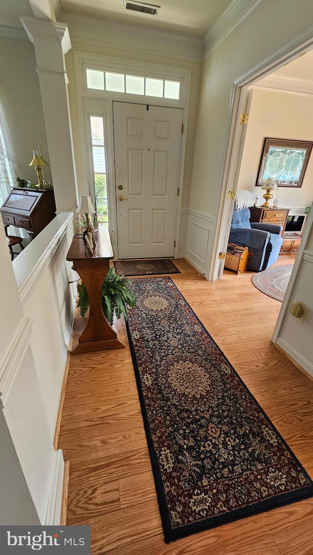 entrance foyer with ornate columns, crown molding, and hardwood / wood-style flooring