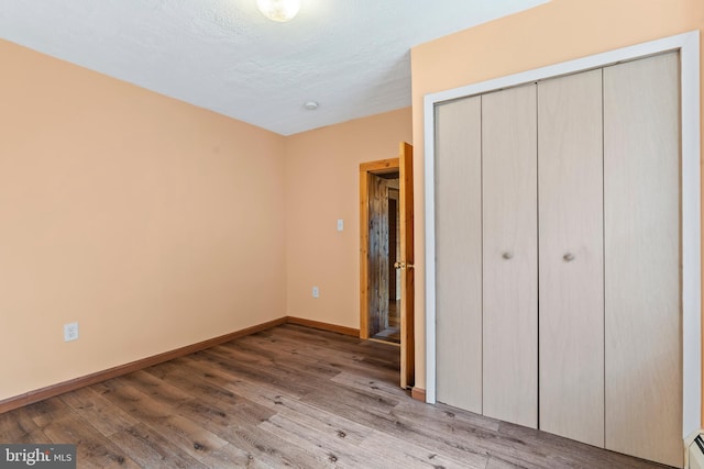 unfurnished bedroom with a closet, light hardwood / wood-style floors, and a baseboard radiator