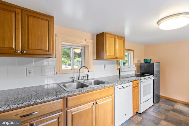 kitchen with stone countertops, sink, a wealth of natural light, and white appliances