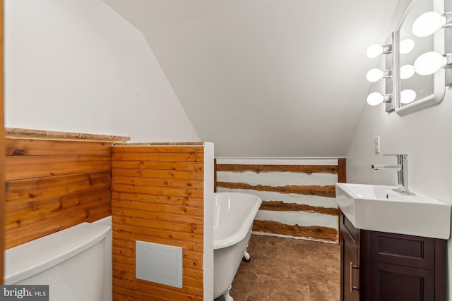 bathroom with vanity, vaulted ceiling, toilet, and a washtub