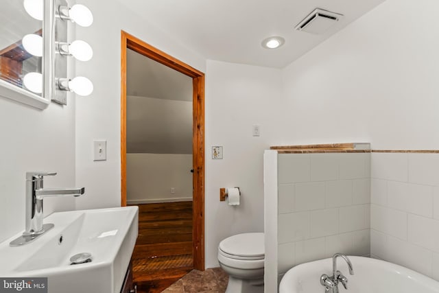 bathroom featuring sink, a bathtub, hardwood / wood-style flooring, and toilet