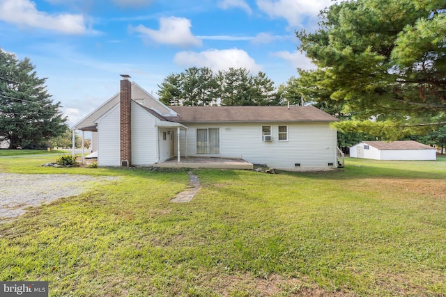 rear view of house with a patio, a lawn, and an outbuilding