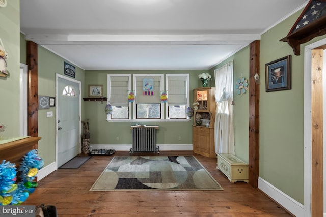 foyer with radiator, crown molding, beamed ceiling, and wood-type flooring
