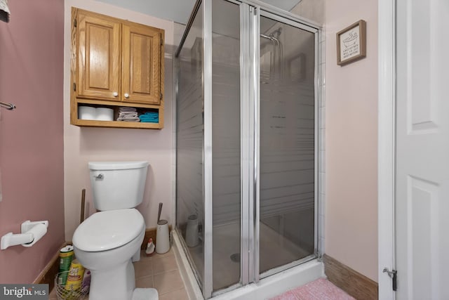 full bathroom featuring baseboards, tile patterned floors, a shower stall, and toilet