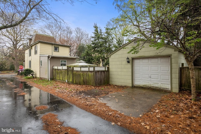 detached garage featuring fence and concrete driveway